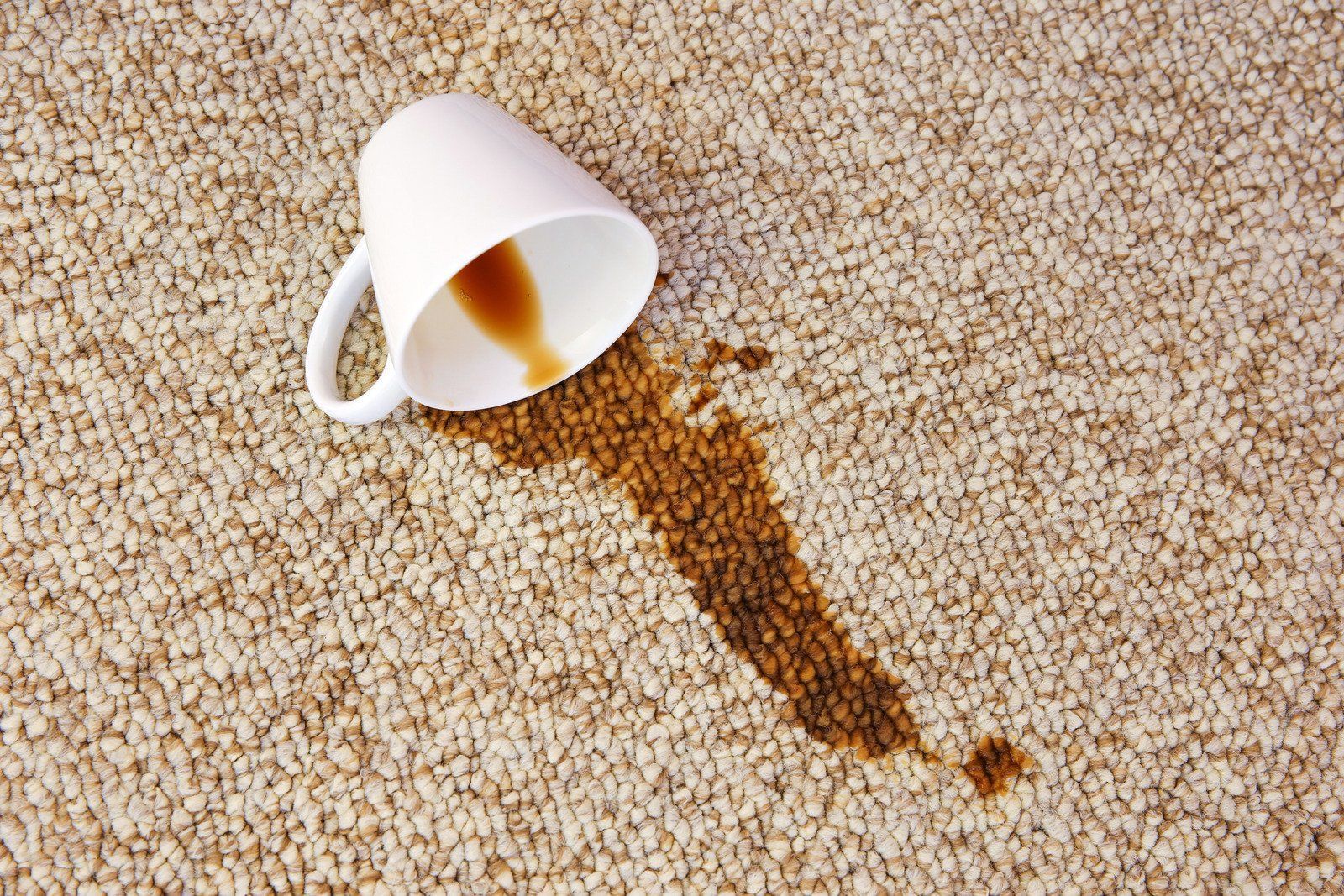 A cup of coffee spilled on a carpet.