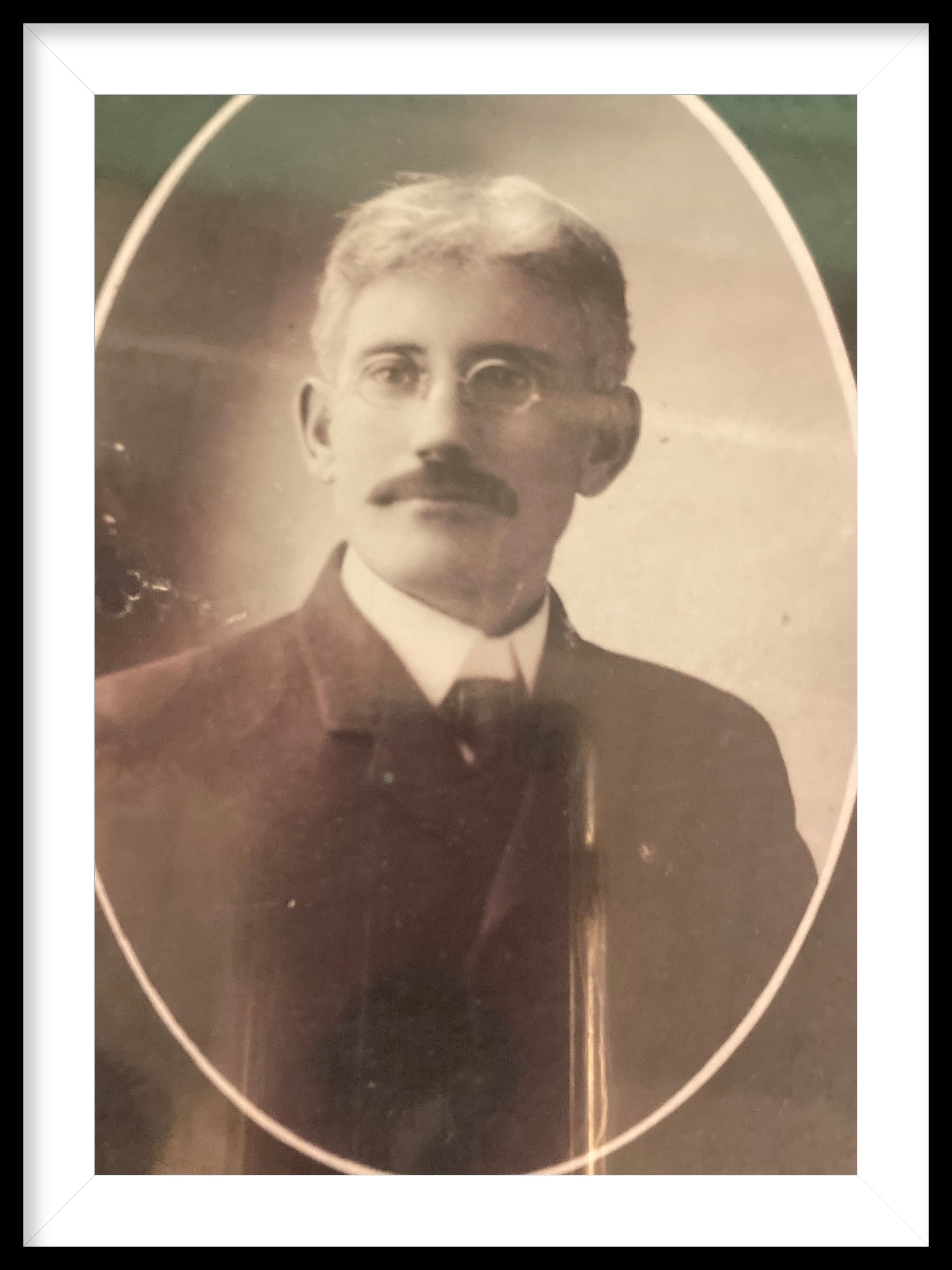 A black and white photo of a man with glasses and a mustache