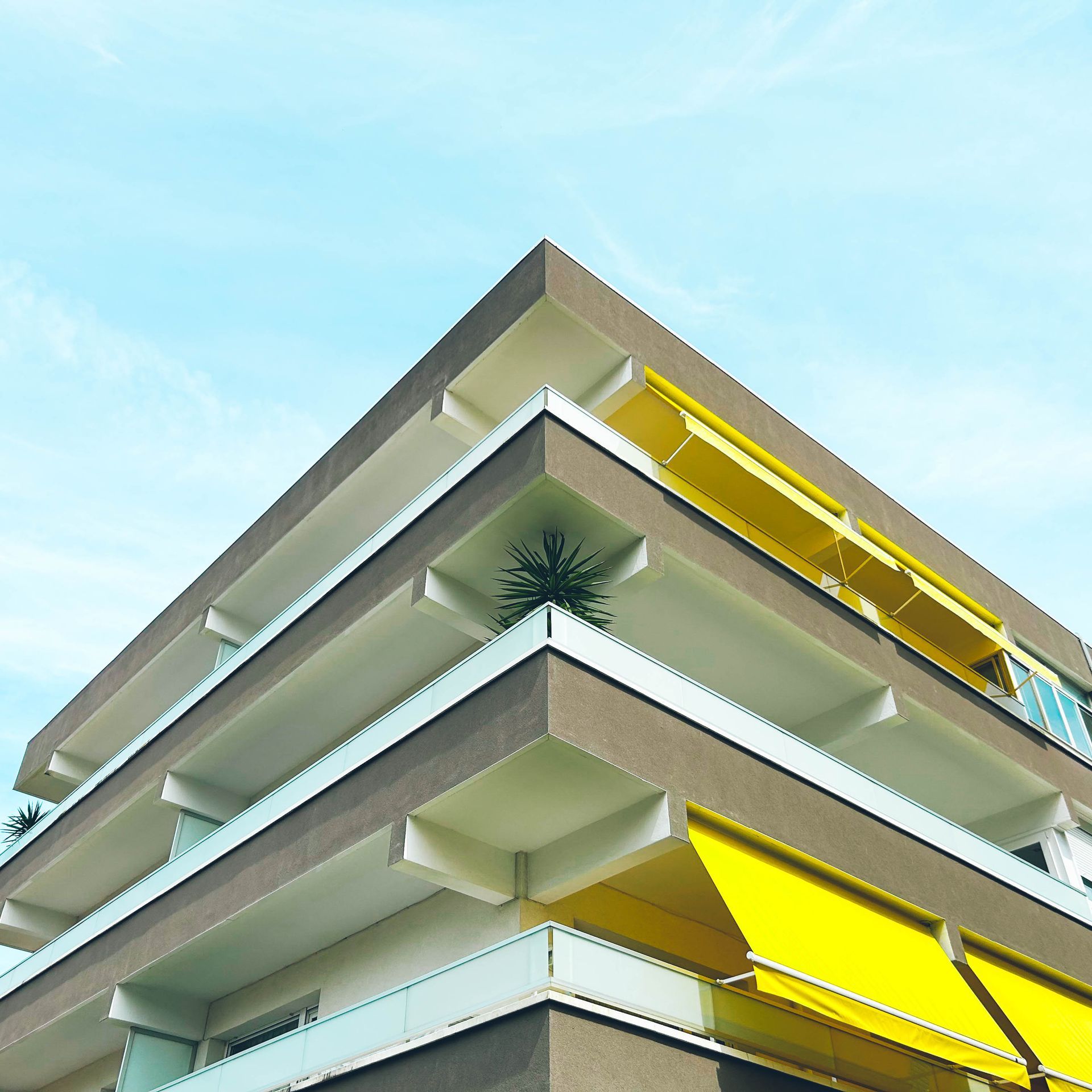 Modern building with yellow awnings and balconies under clear blue sky.