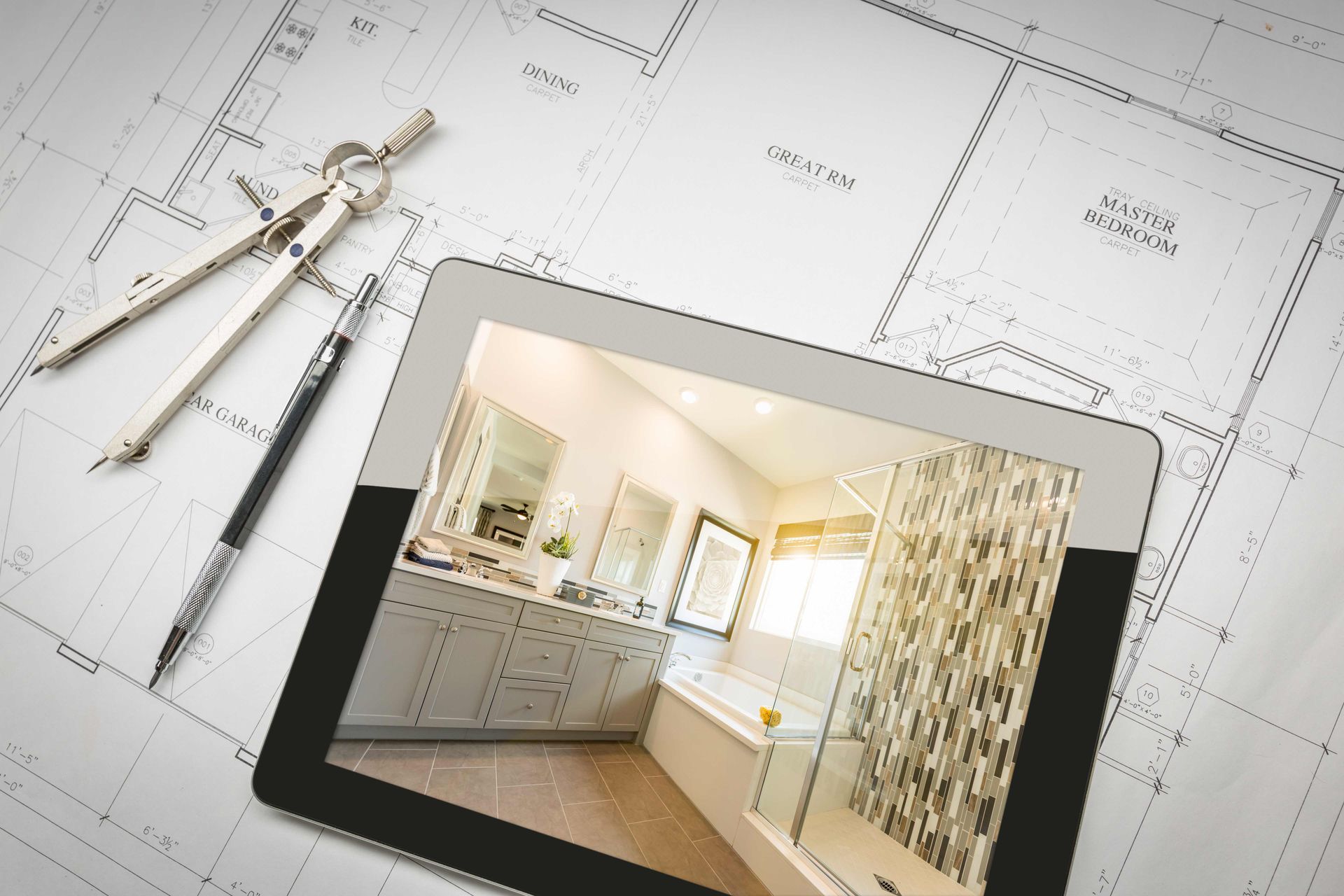 Tablet showing a modern bathroom design on top of home construction blueprints. Tablet showing a modern bathroom design on top of home construction blueprints.