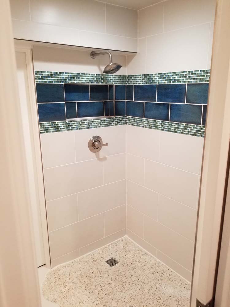 A shower with blue and green tiles and a shower head.