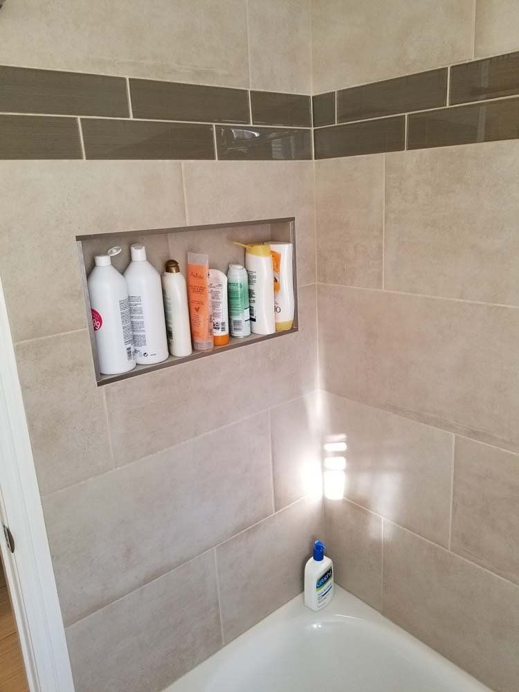A bathroom with a tub and a shelf filled with bottles of shampoo and conditioner.