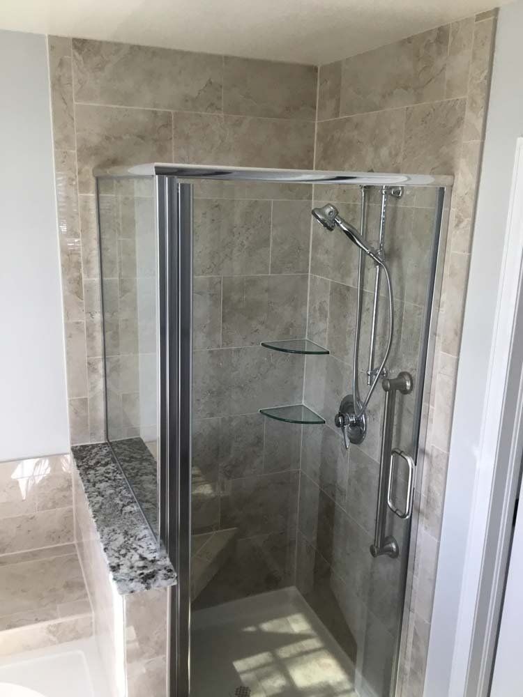 A bathroom with a walk in shower with a glass door.