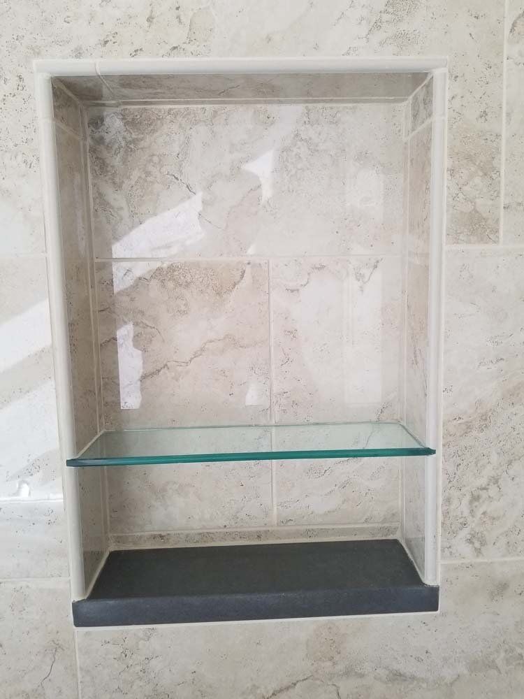 A bathroom shelf with a glass shelf and a black shelf.