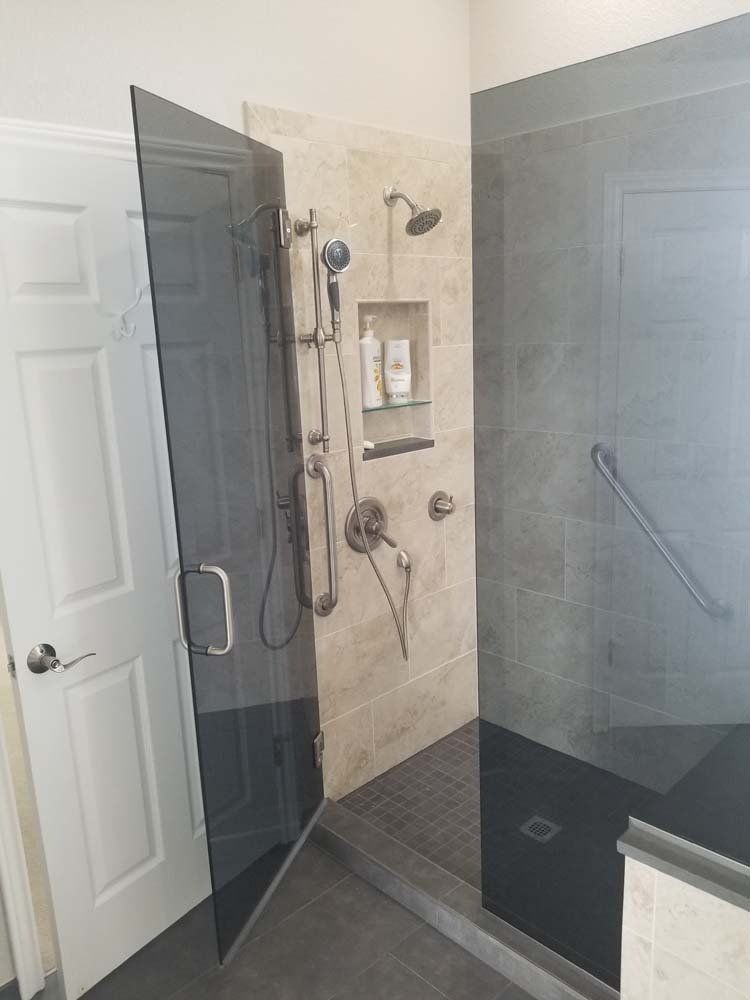A bathroom with a walk in shower with a glass door.