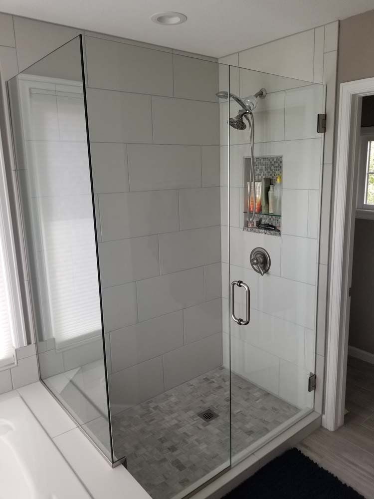 A bathroom with a walk in shower with a glass door and a shower head.