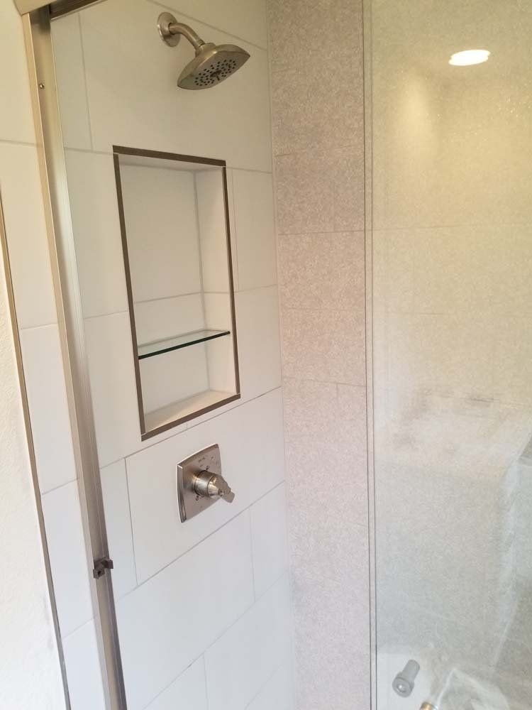 A shower with a glass door and a shower head on the wall.