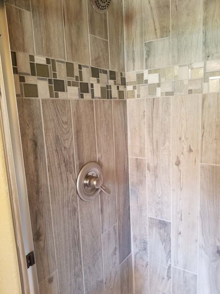 A shower with wooden tiles and a stainless steel shower head.