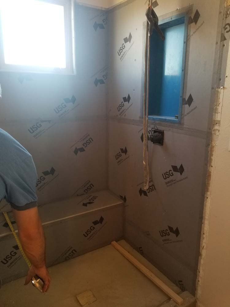 A man is measuring a bathroom with a tape measure.