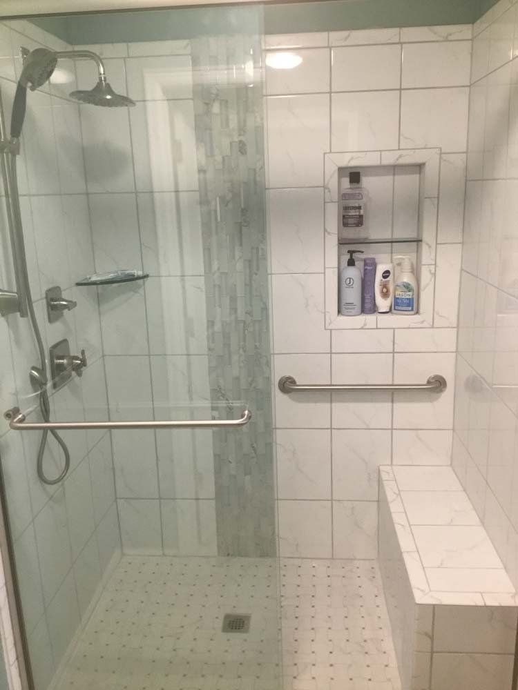 A bathroom with a walk in shower and a bench.
