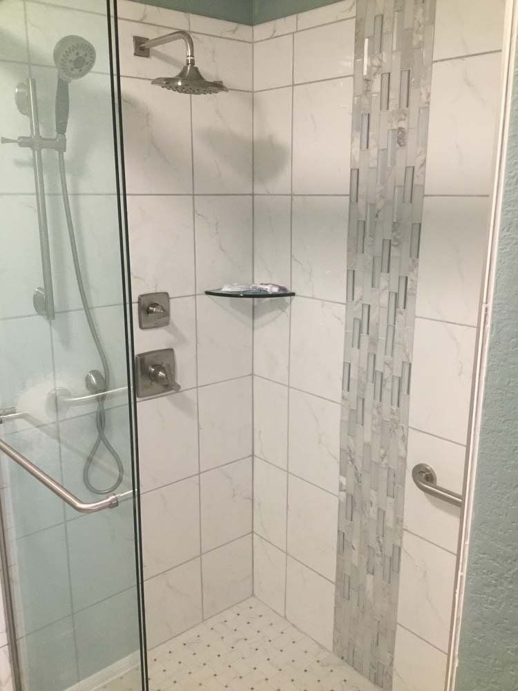 A walk in shower with a glass door and a shower head.