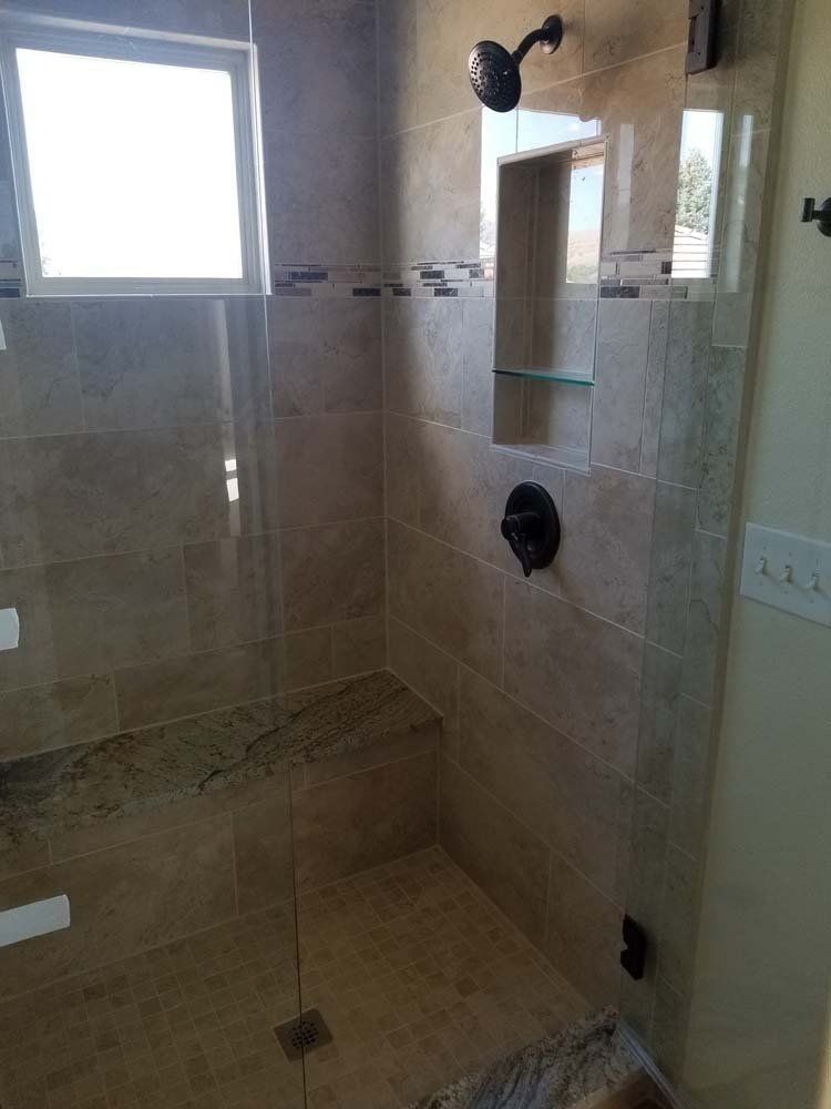 A bathroom with a walk in shower with a glass door and a window.