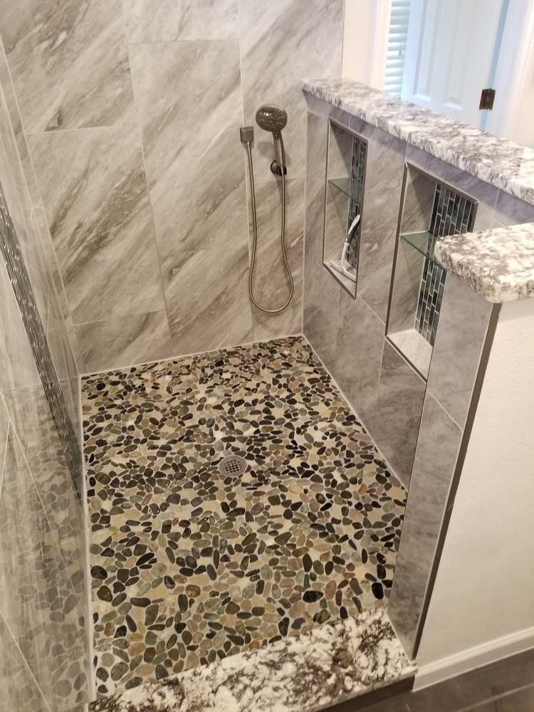 A bathroom with a walk in shower and a marble counter top.