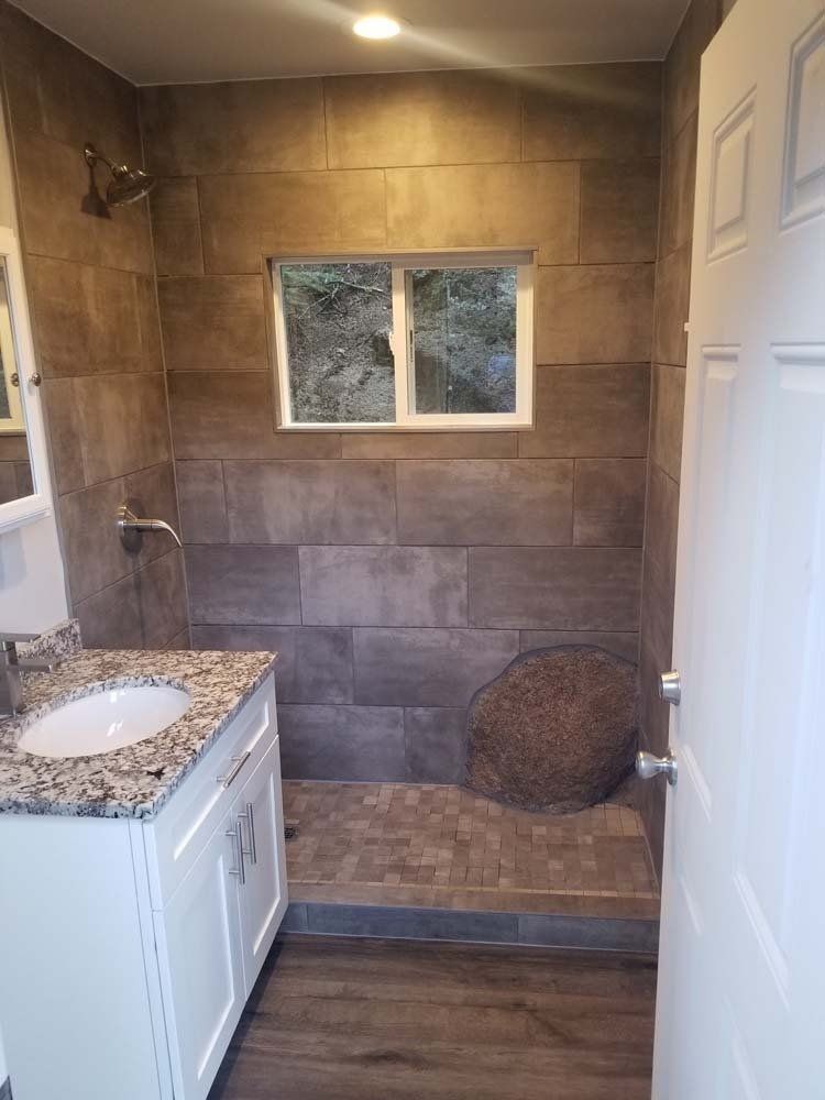 A bathroom with a sink , shower and window.