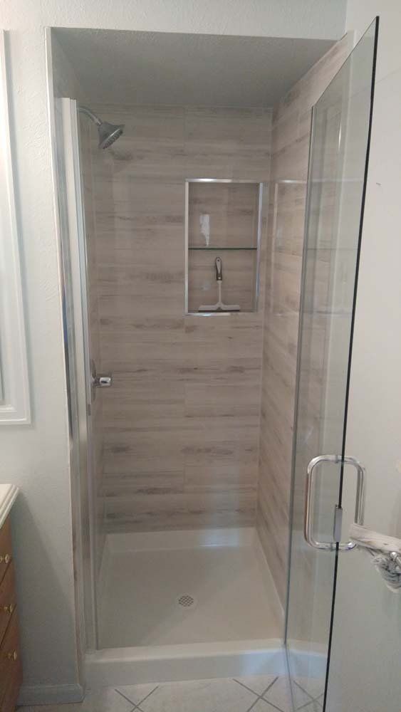 A bathroom with a walk in shower and a glass door.