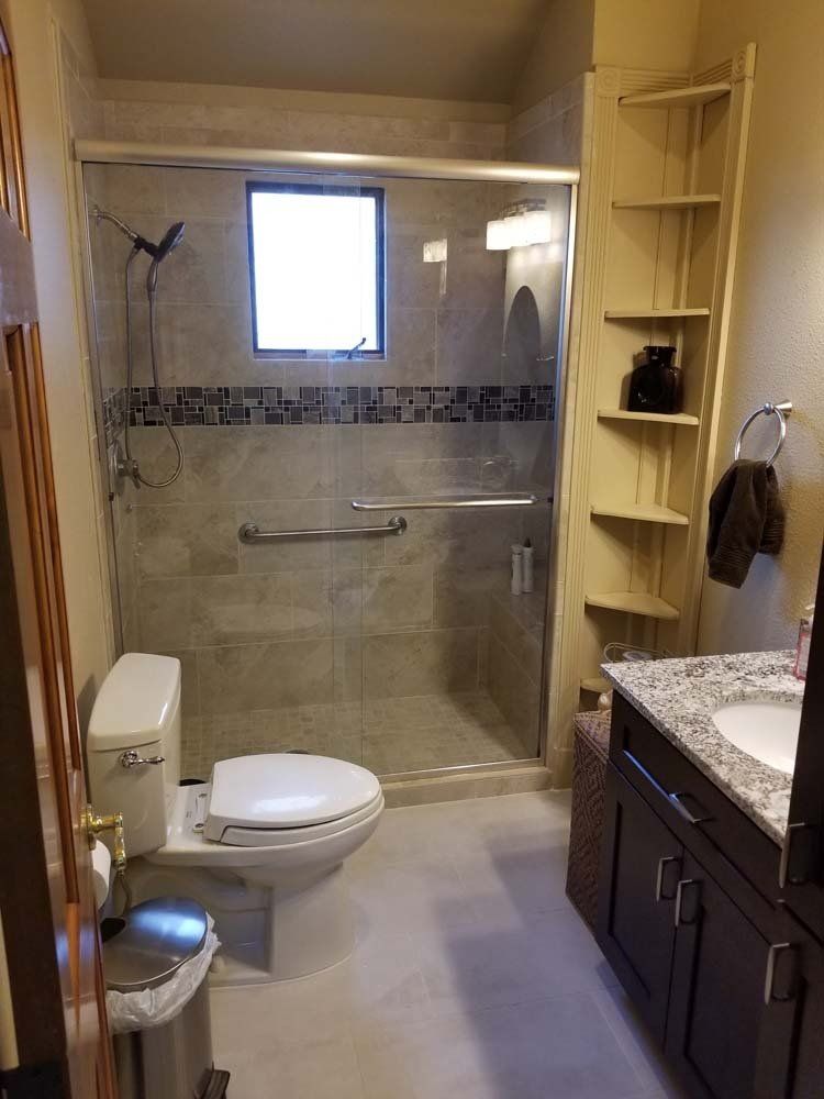 A bathroom with a toilet , sink , shower and window.