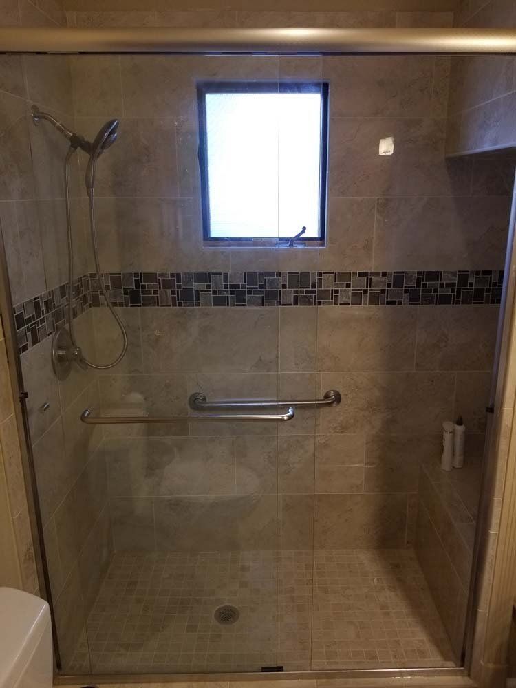 A bathroom with a sliding glass shower door and a window.