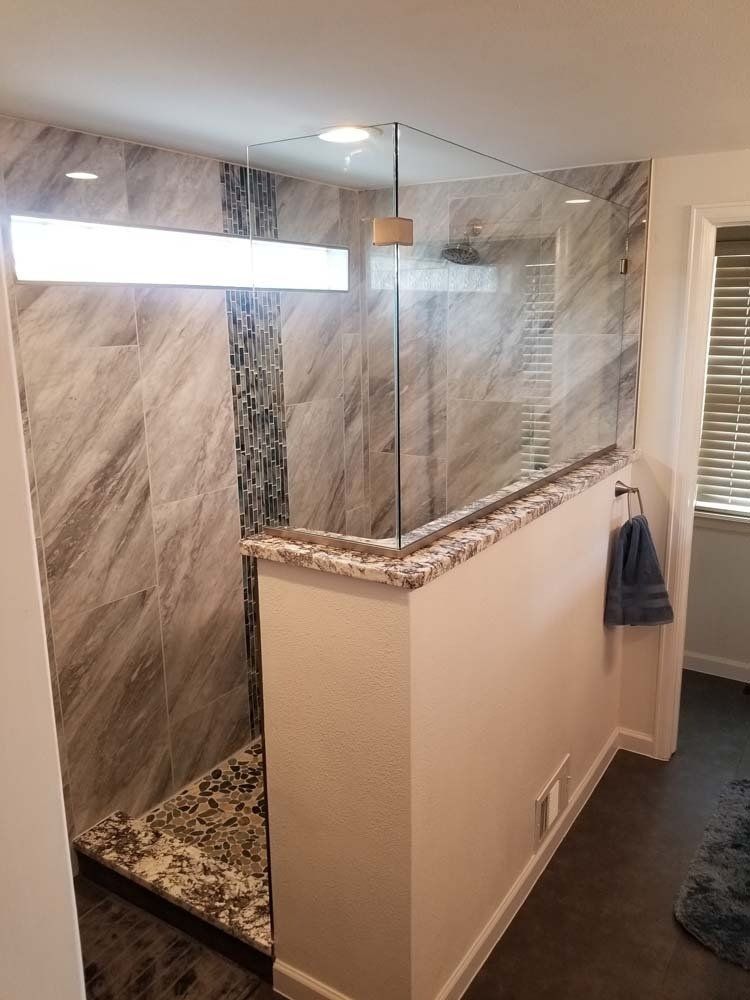 A bathroom with a walk in shower with a glass door.