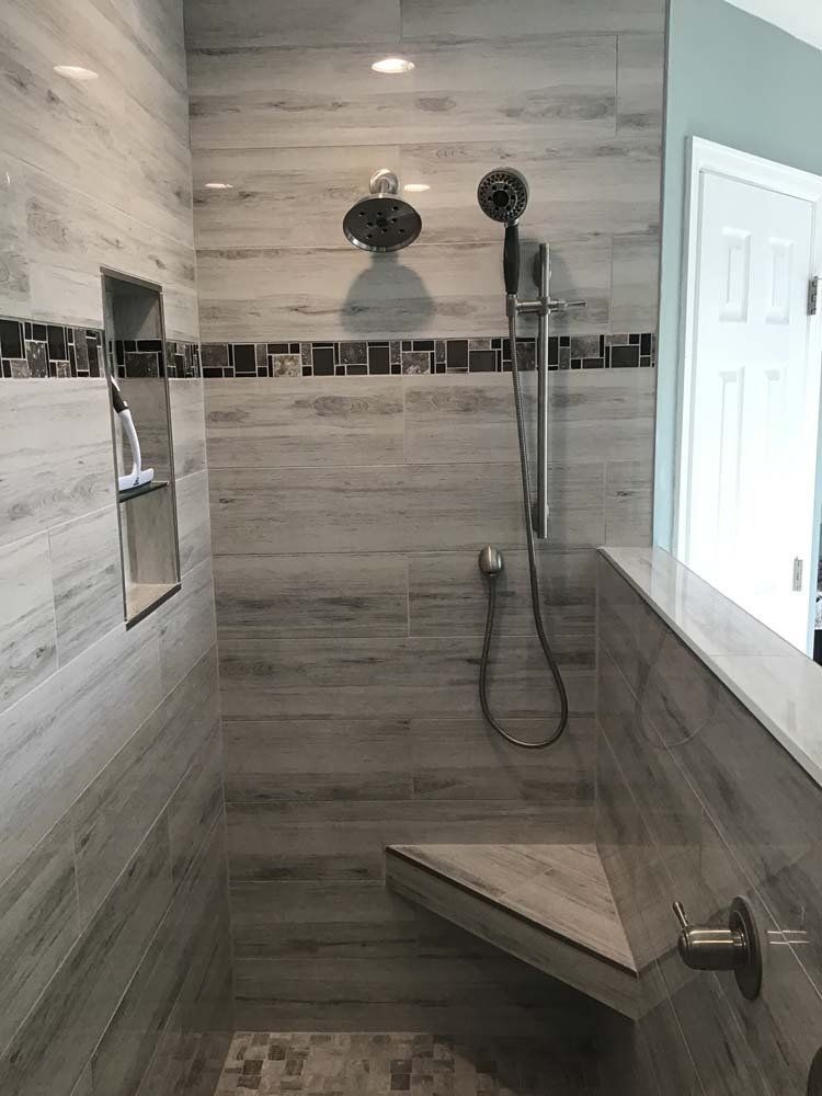 A bathroom with a walk in shower and a bench.