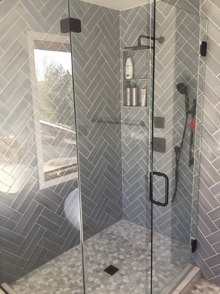 A bathroom with a walk in shower with a glass door.