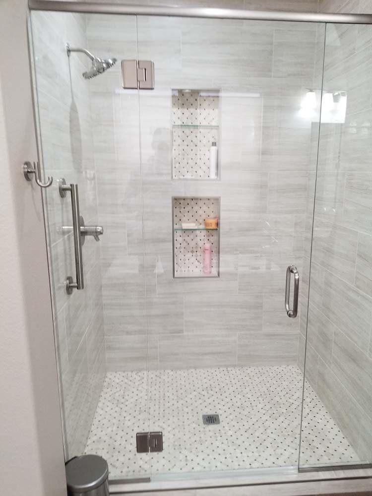 A shower stall with a sliding glass door and a shower head.