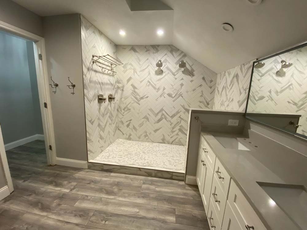 A bathroom with a walk in shower , sink and mirror.