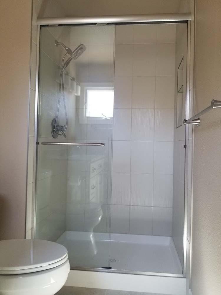 A bathroom with a toilet and a shower with a sliding glass door.