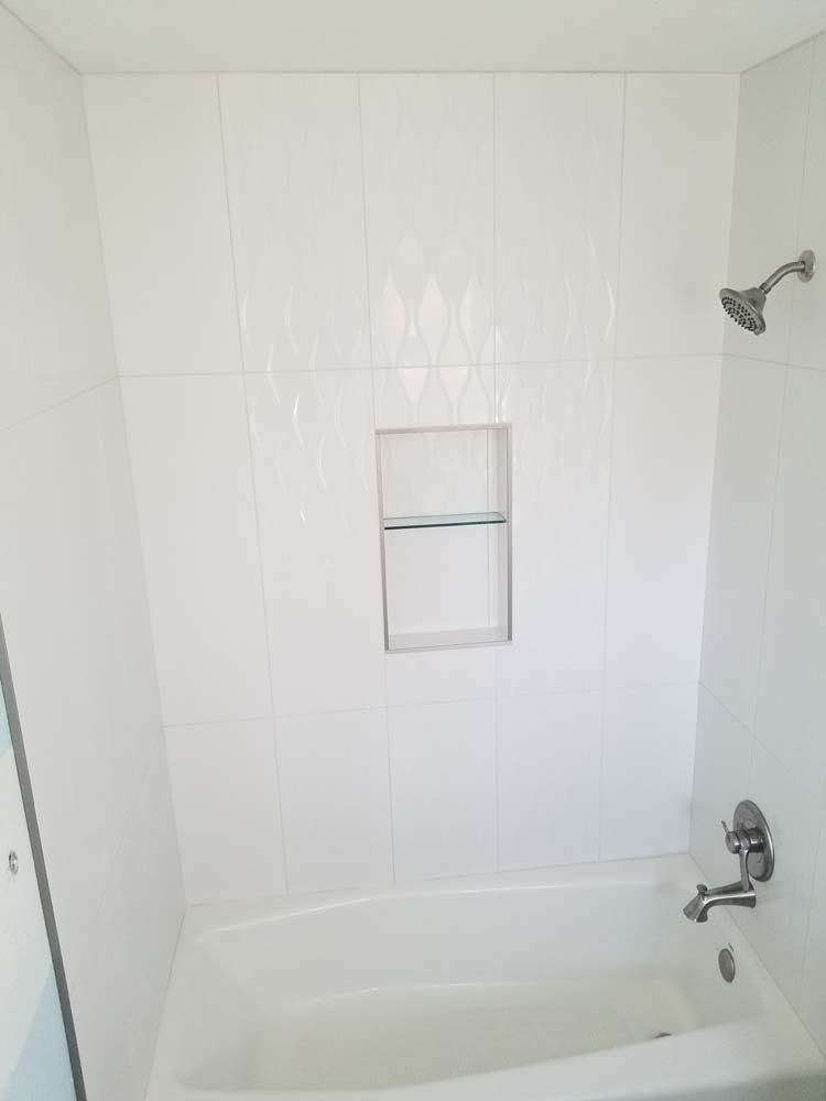 There is a bathtub in the shower with a shower head.
