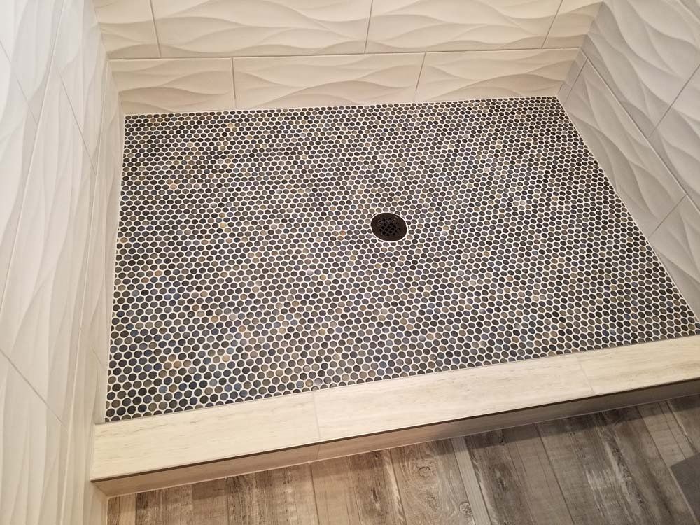 A shower stall with a black hole in the middle of it.