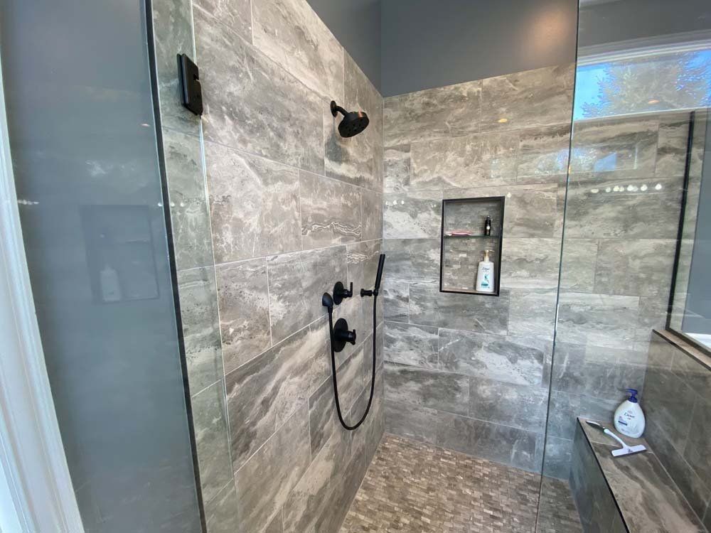 A bathroom with a walk in shower with a glass door.
