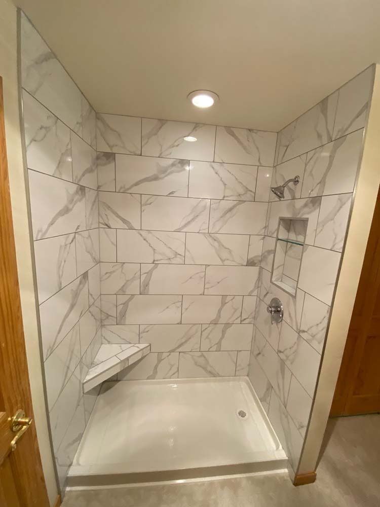 A bathroom with marble tiles and a walk in shower.