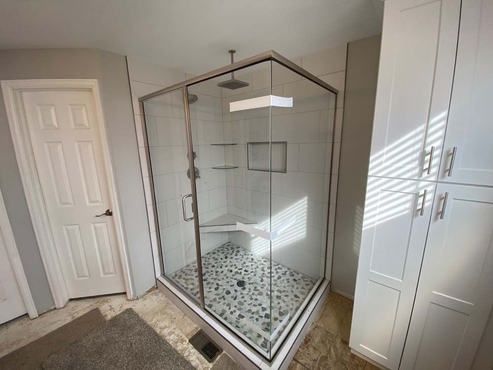 A bathroom with a walk in shower with a glass door.