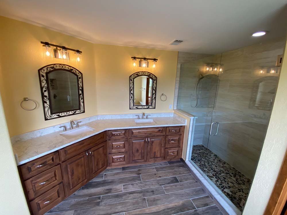 A bathroom with two sinks and a walk in shower.