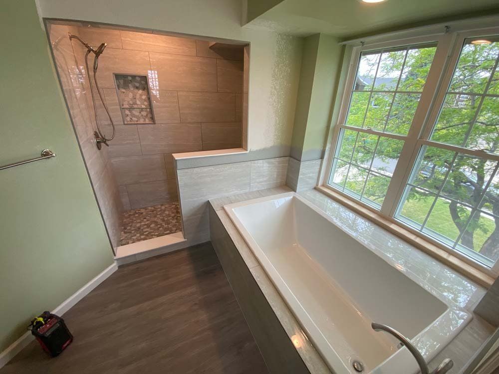 A bathroom with a tub , shower , and window.