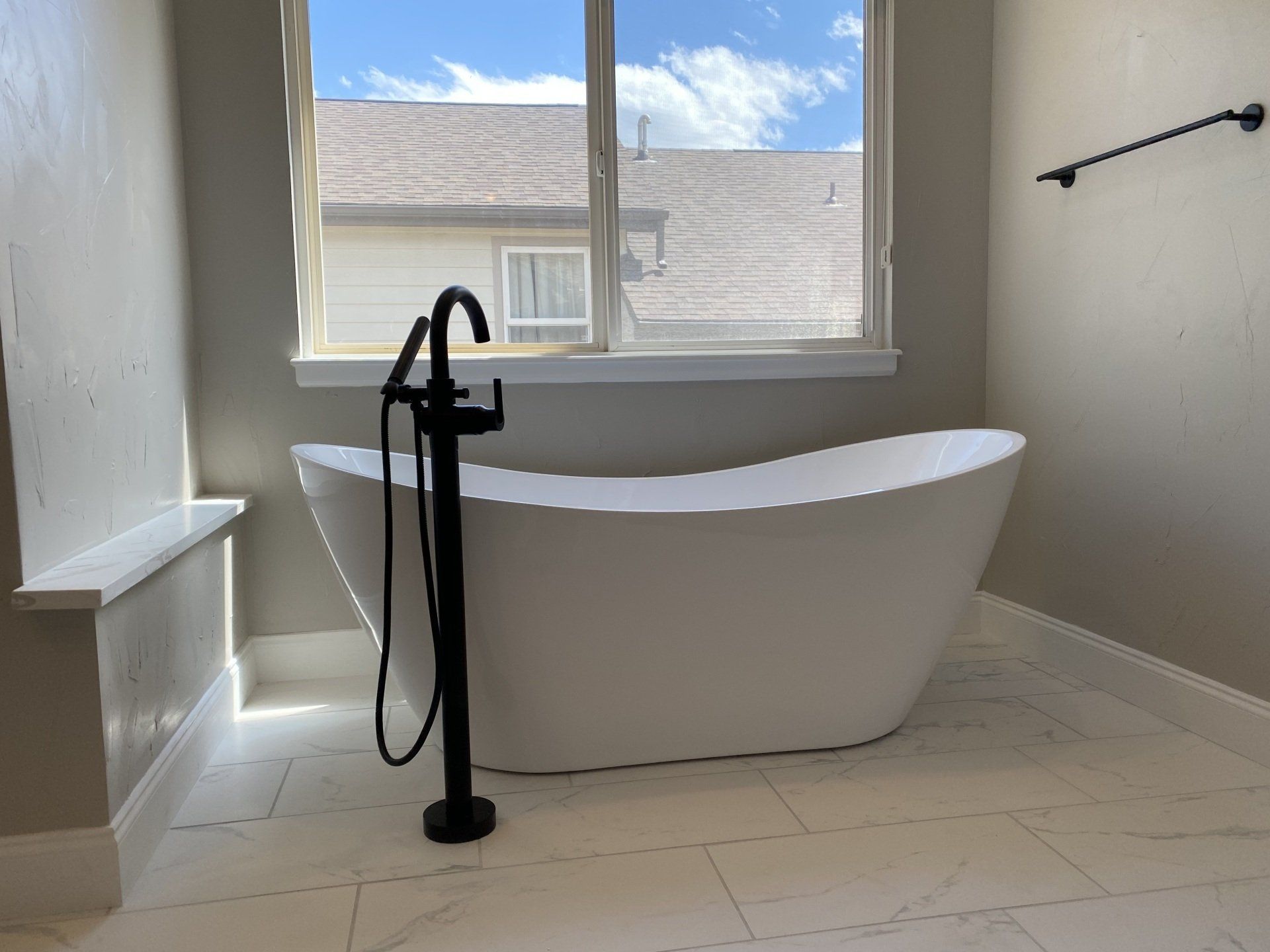 A bathtub in a bathroom next to a window.
