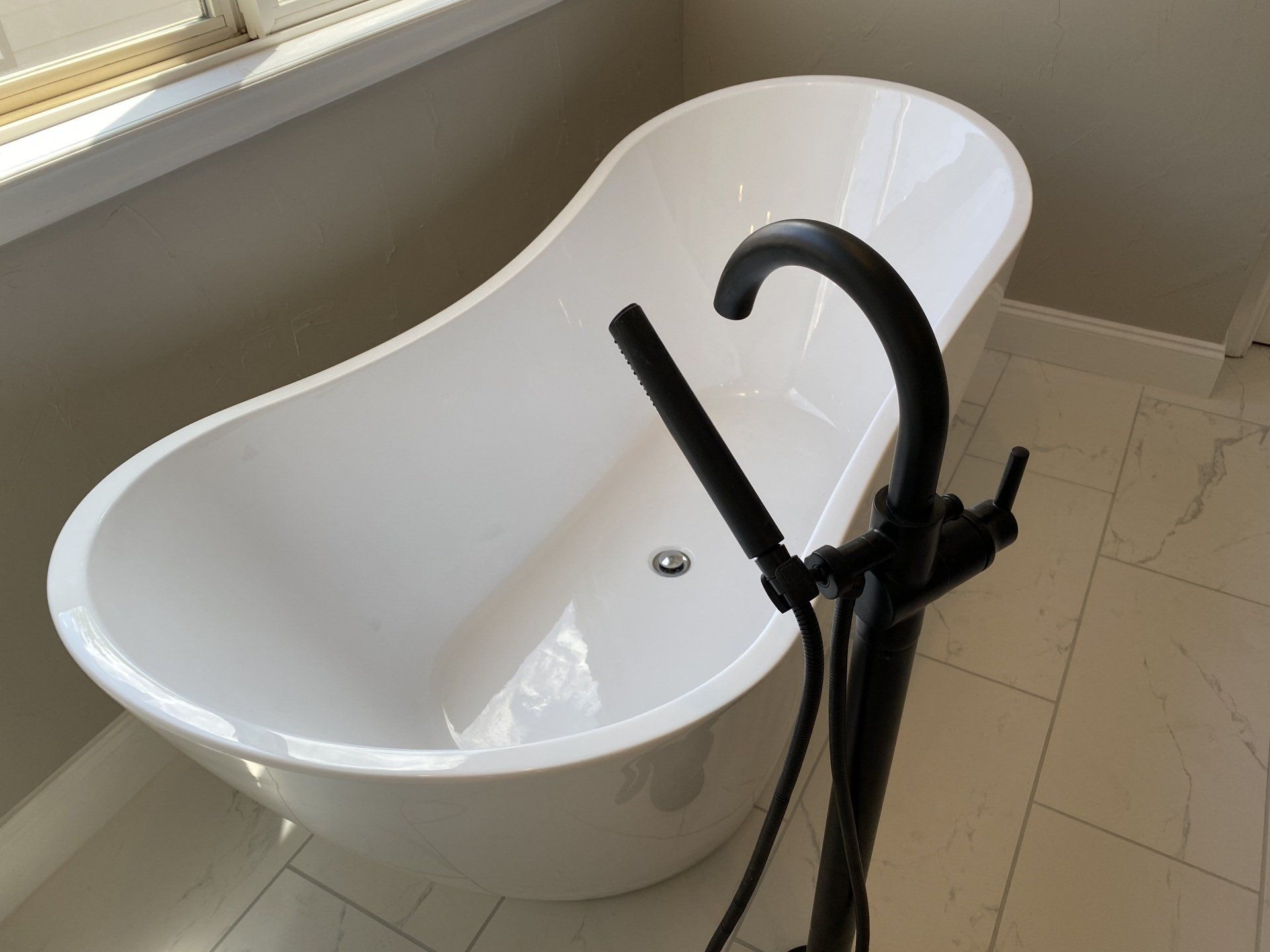 A white bathtub with a black faucet in a bathroom
