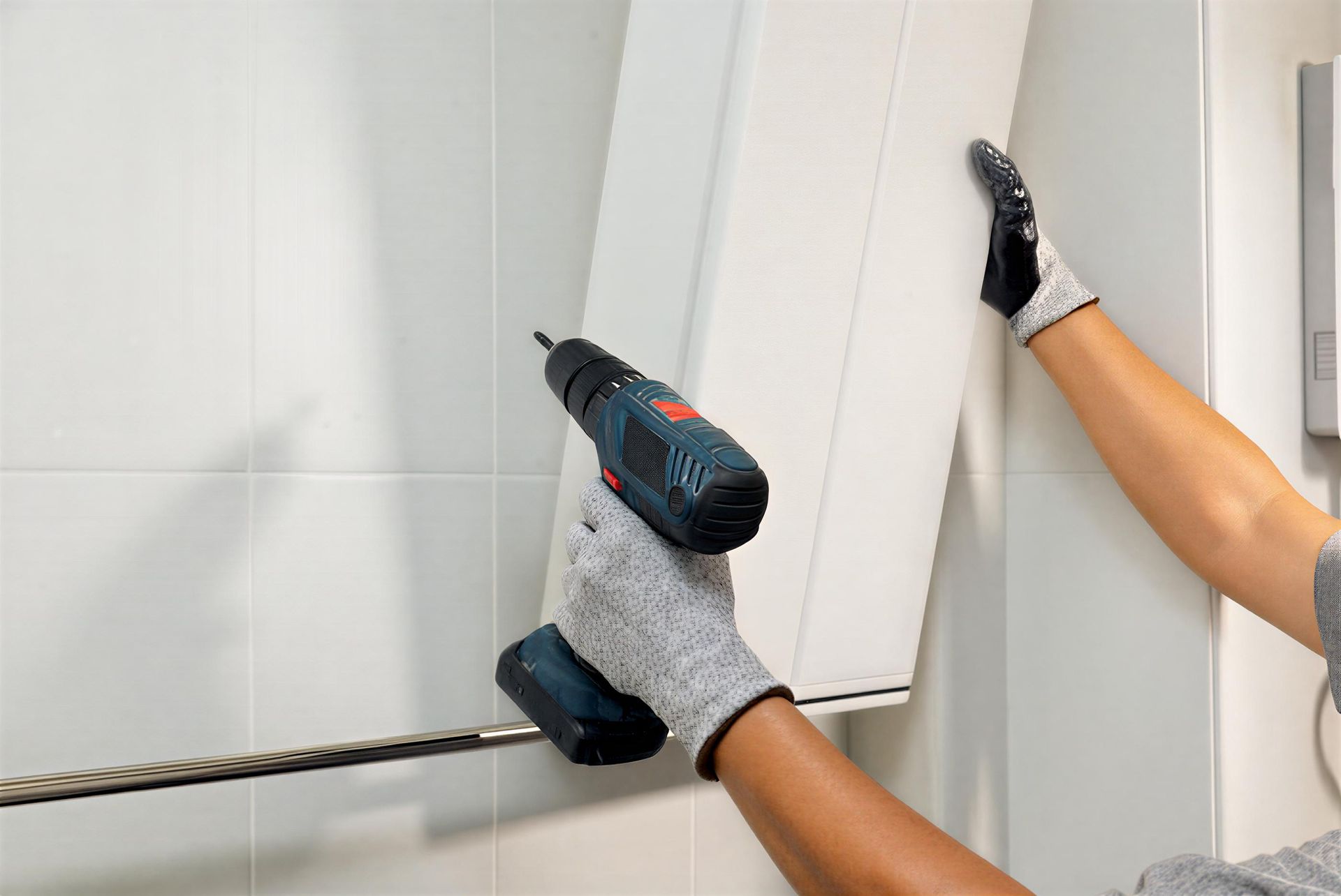 Handyman installing cabinet on bathroom wall.