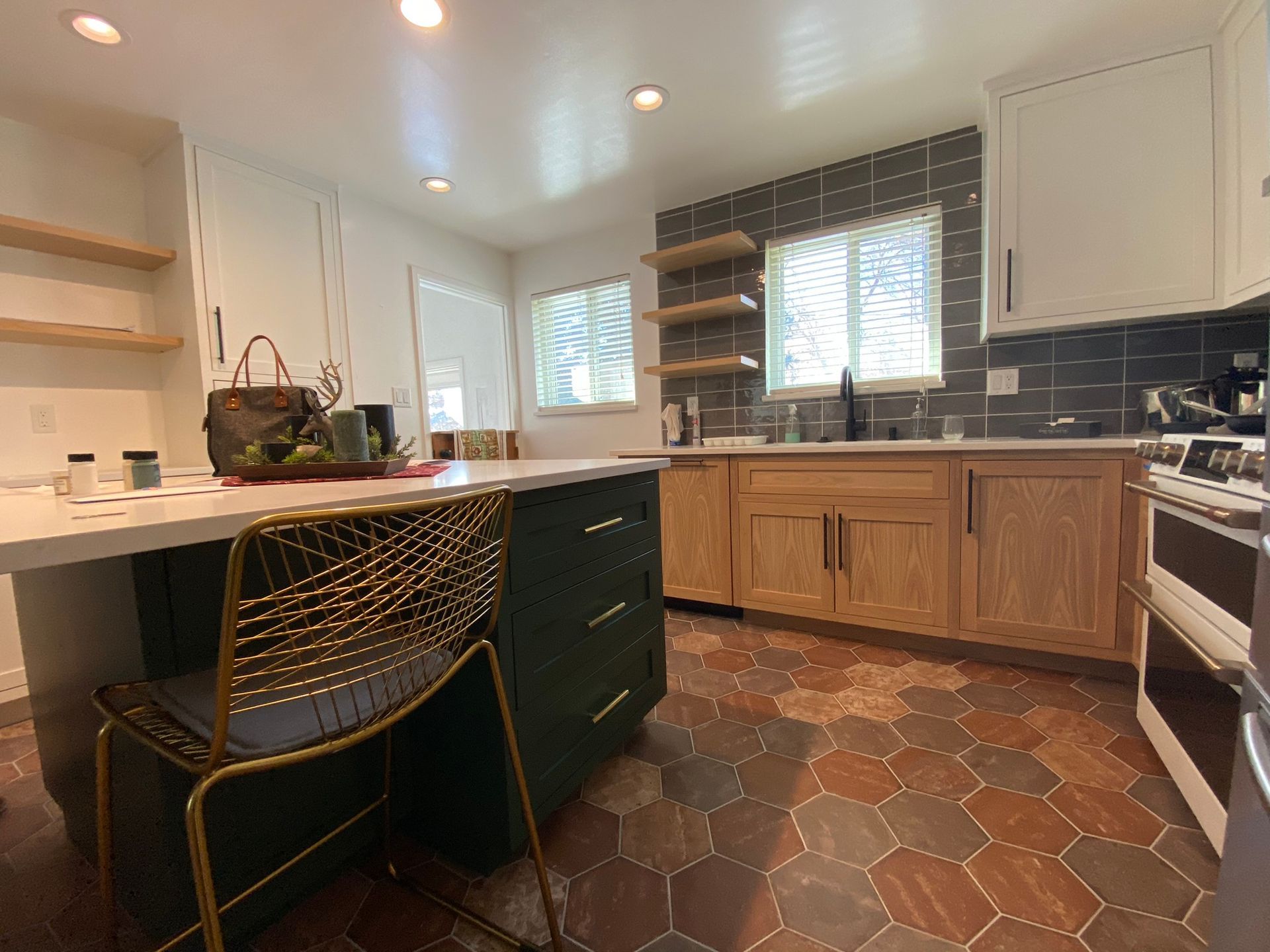 A kitchen with a stove , sink , cabinets and a chair.