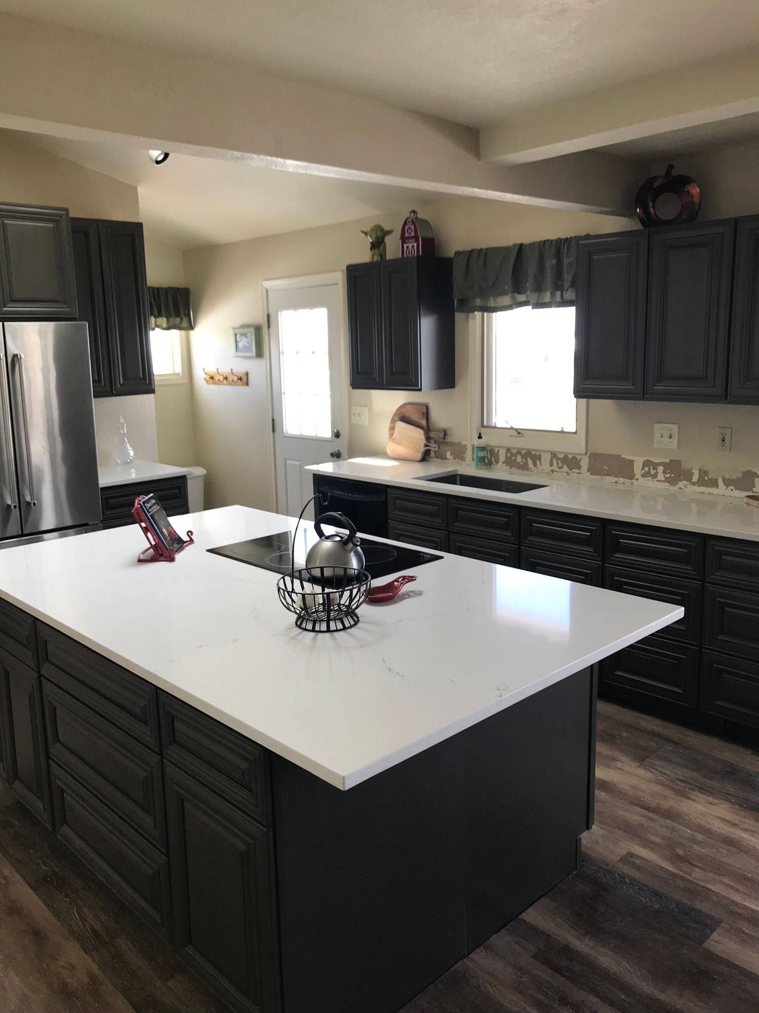 Modern kitchen with dark cabinets, white countertops, and stainless steel appliances.