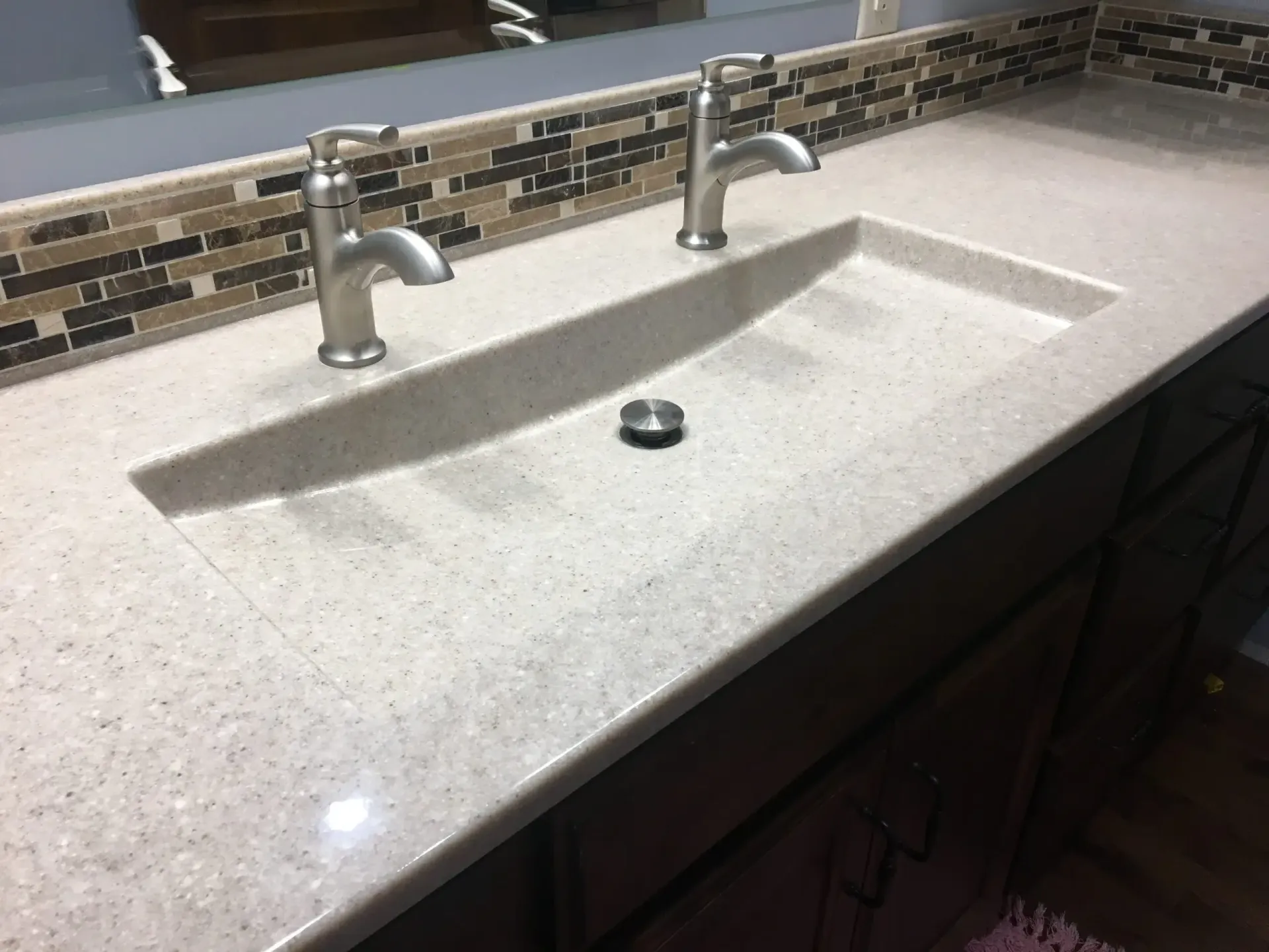 A bathroom sink with two faucets and a mirror