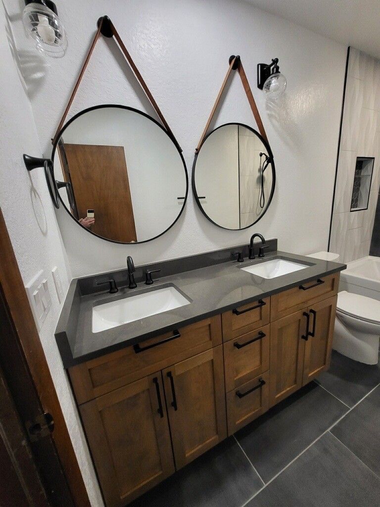 A bathroom with two sinks , two mirrors and a toilet.