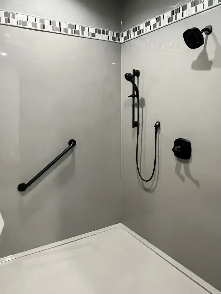 A shower with a black handle and a black shower head.