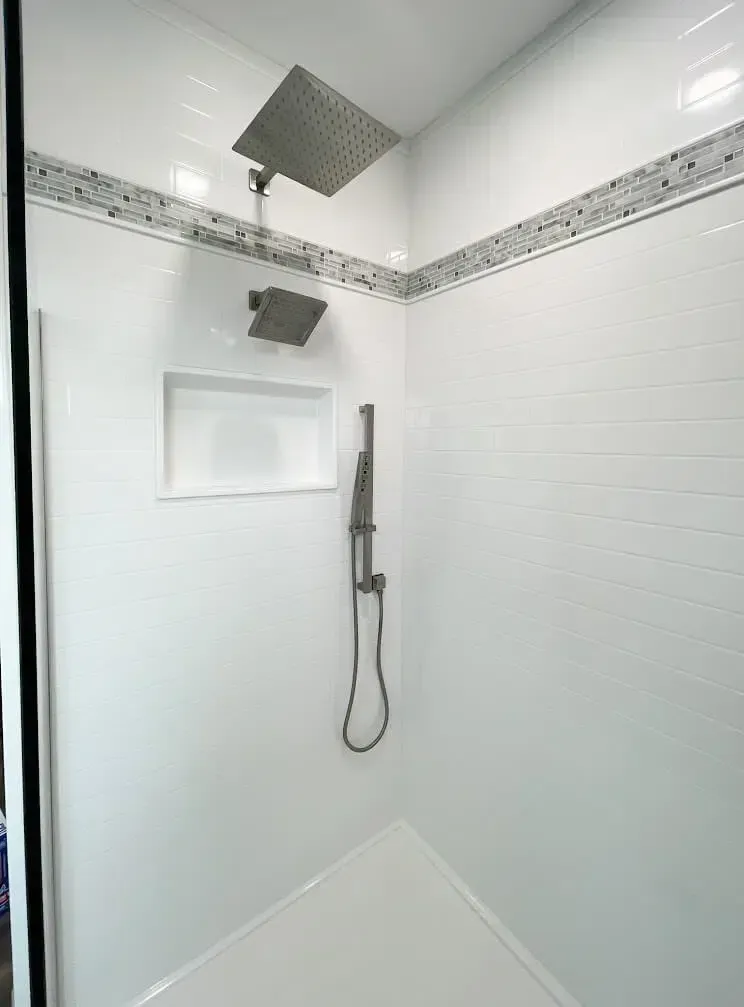 A shower with two shower heads and a shower head hanging from the ceiling.