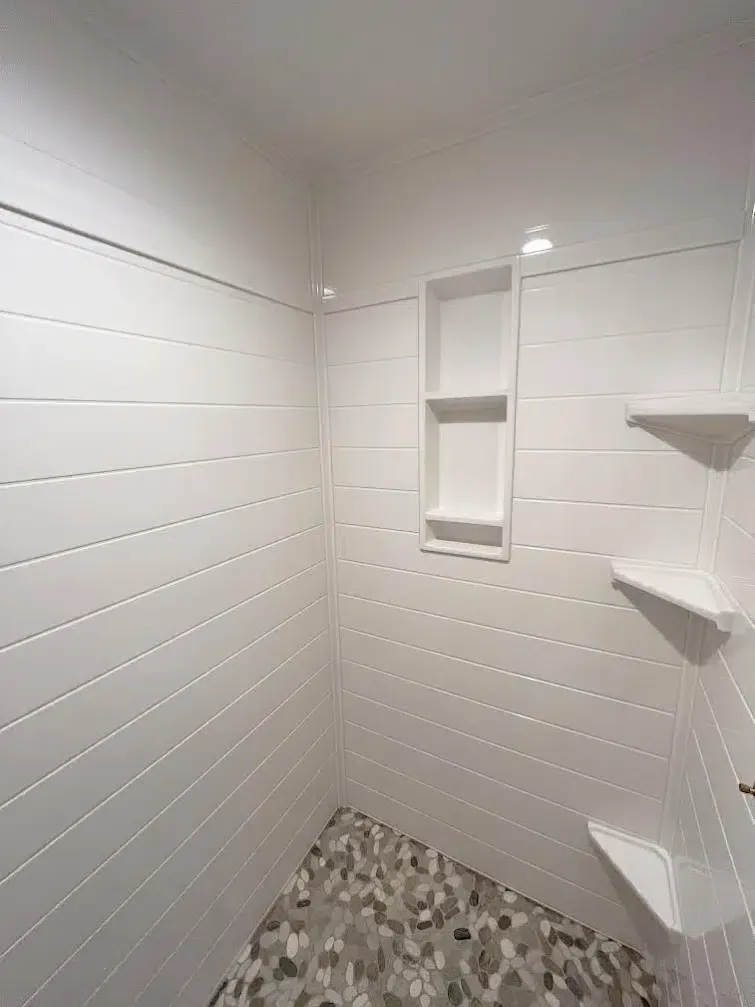 A bathroom with white tile walls and a mosaic floor.