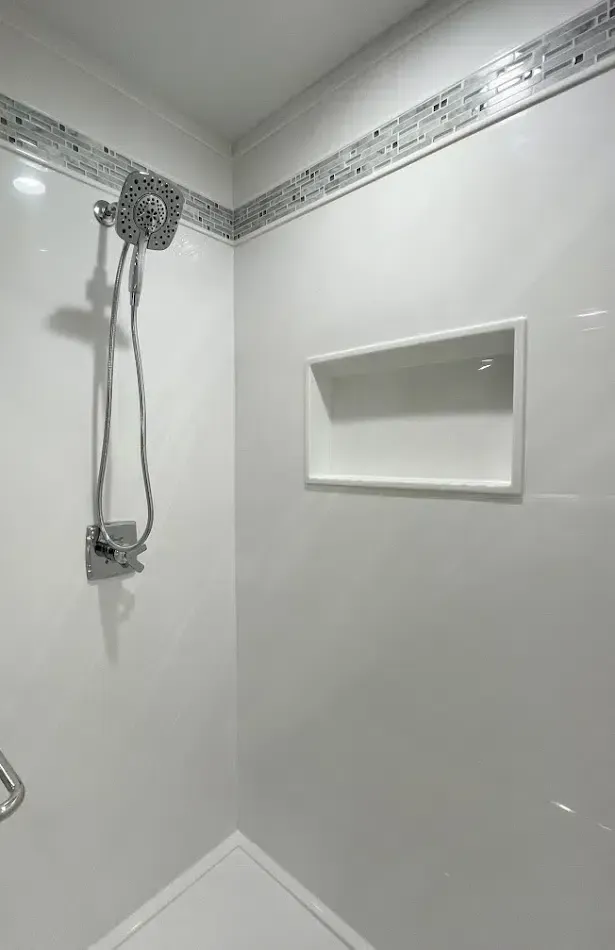 A shower with a shower head and a shelf on the wall.