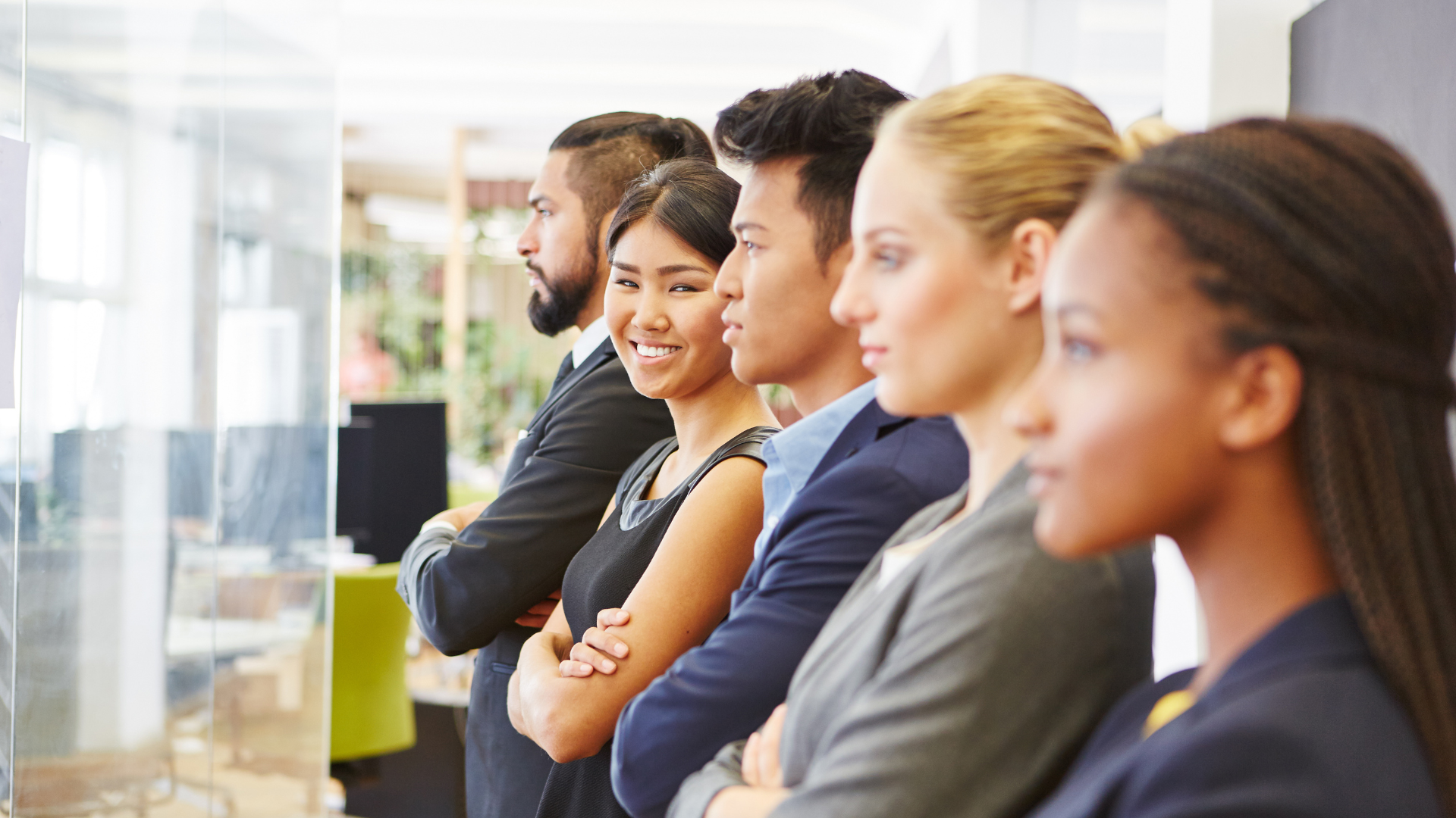 A group of business people are standing in a row with their arms crossed.