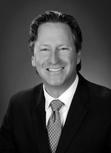 Allen Engstrom in a suit and tie is smiling in a black and white photo.