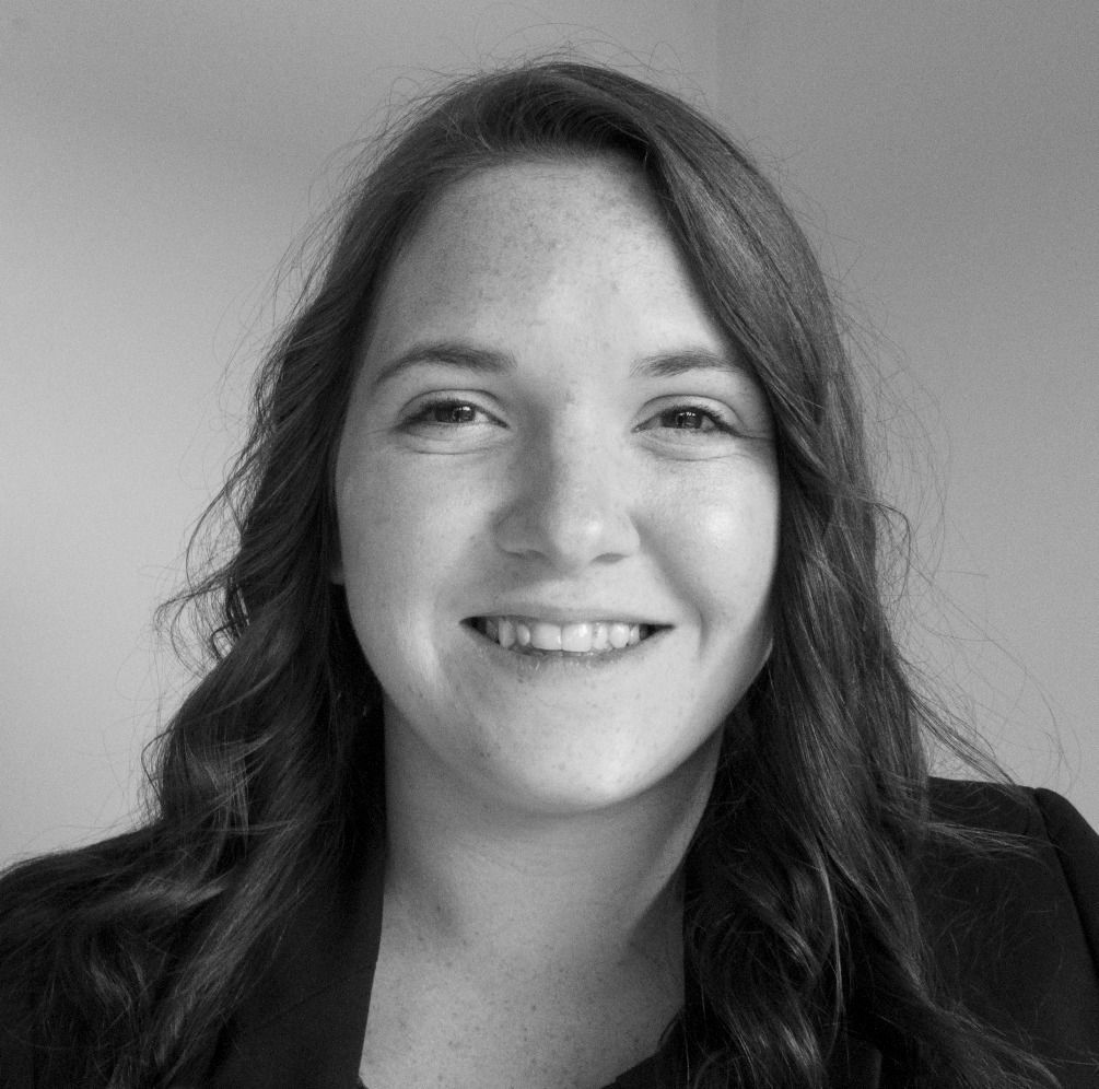 A woman with long hair is smiling in a black and white photo.