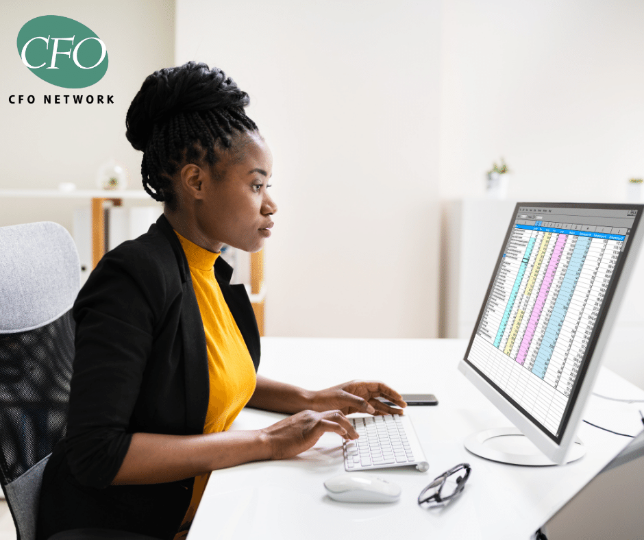 A woman is sitting at a desk using a computer creating a financial budget