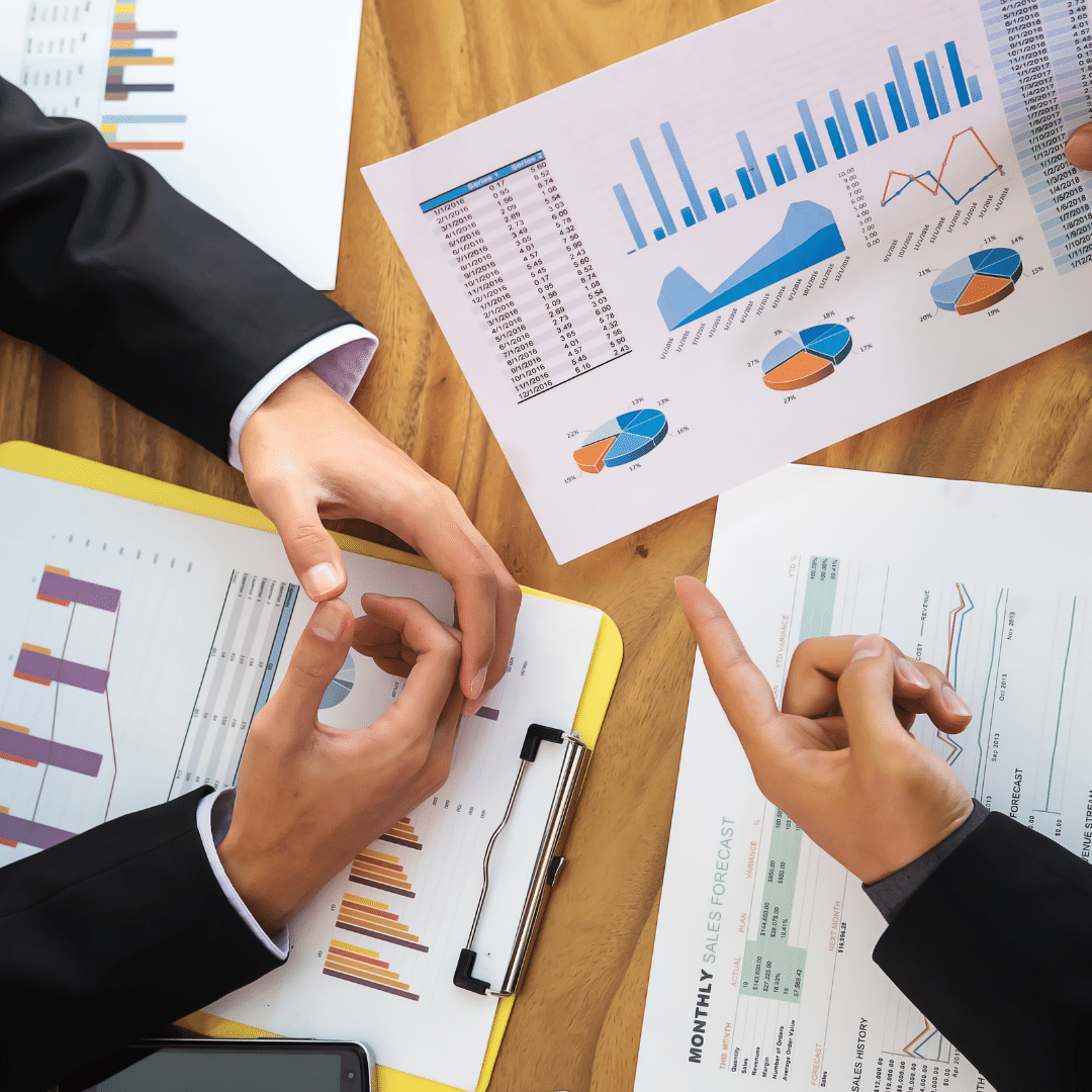 Two people are sitting at a table looking at charts and graphs.